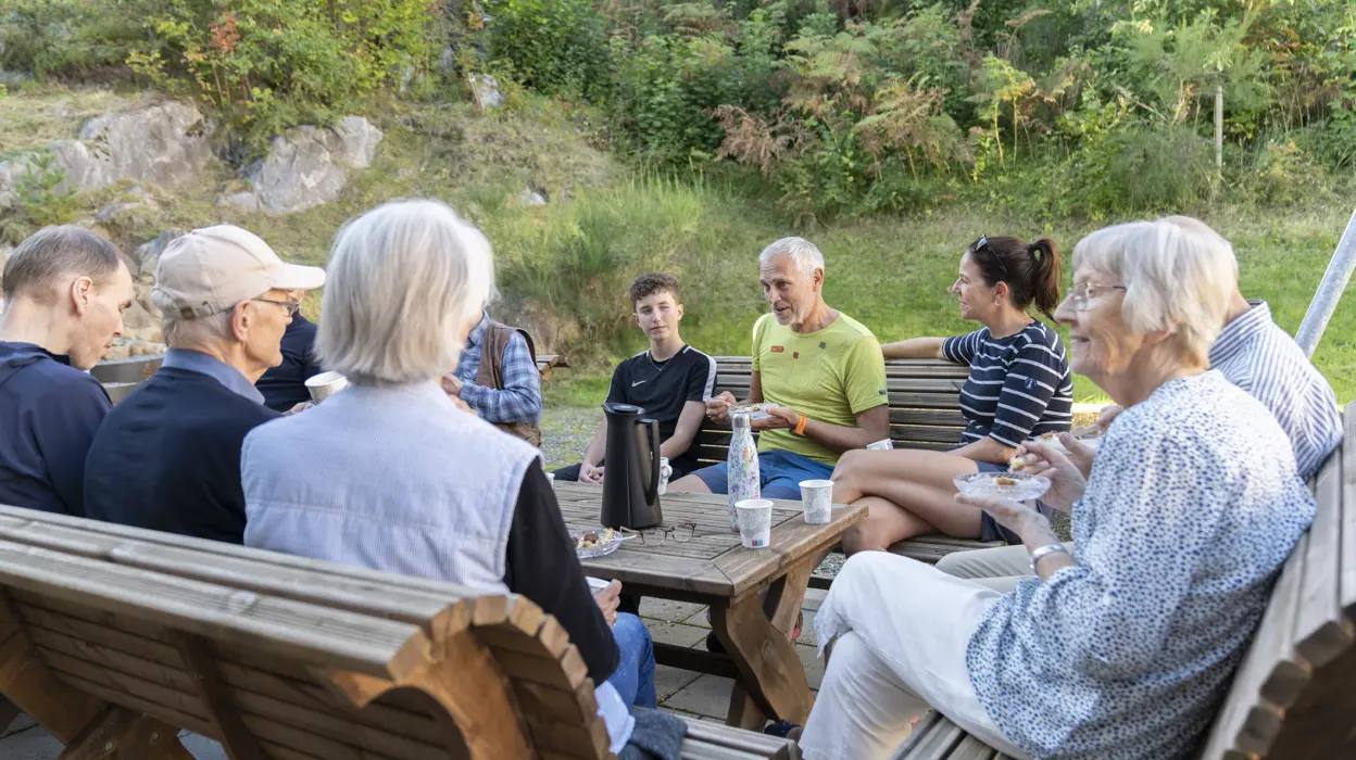 Folk fra samme boligblokk koser seg og drikker kaffe i felles hage