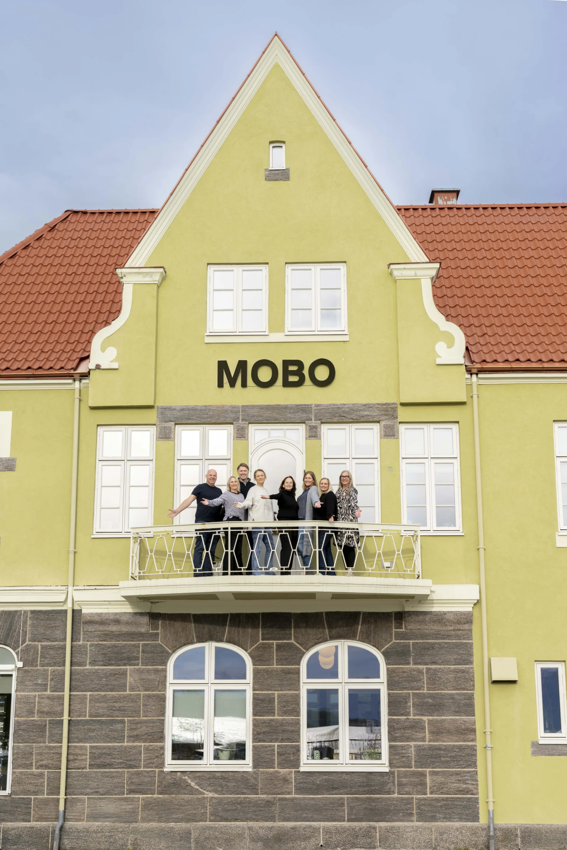 gruppe mennesker står på balkong og vinker